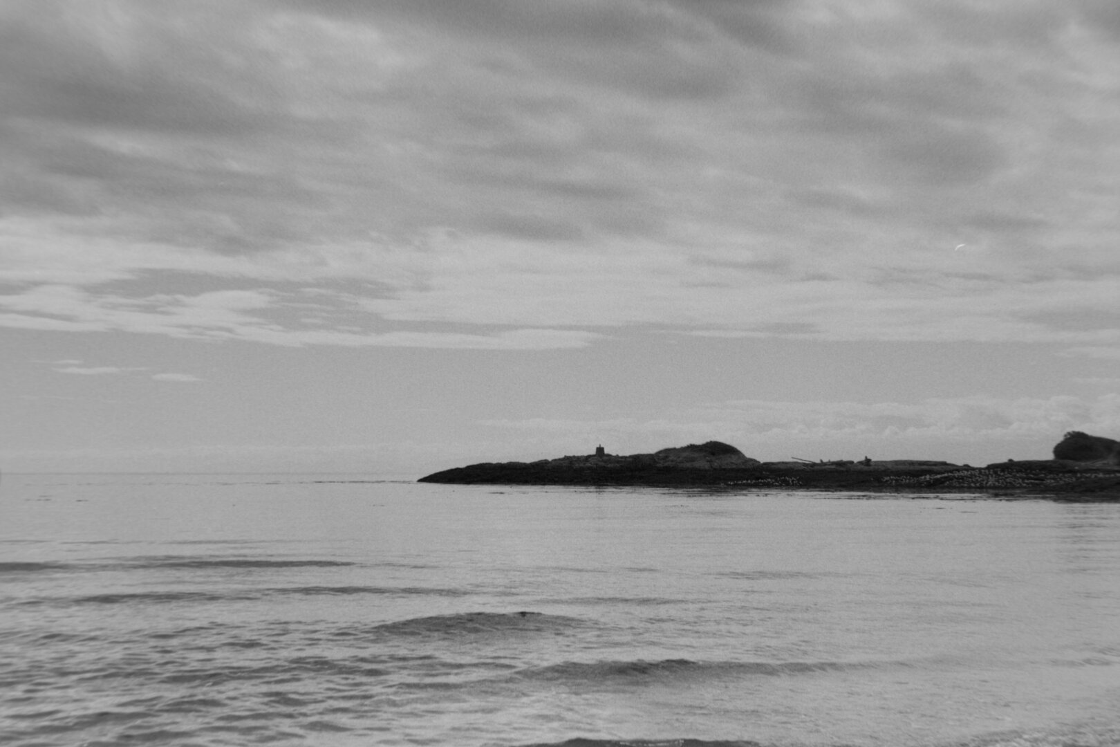 Another view from the shore, this one the sky is blown out with vibrant whites and the island a dark silhouette.