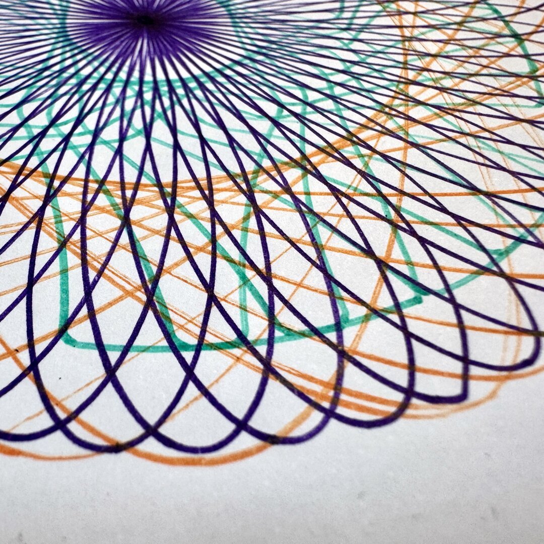 Loops drawn in purple, green and orange pen on white paper.