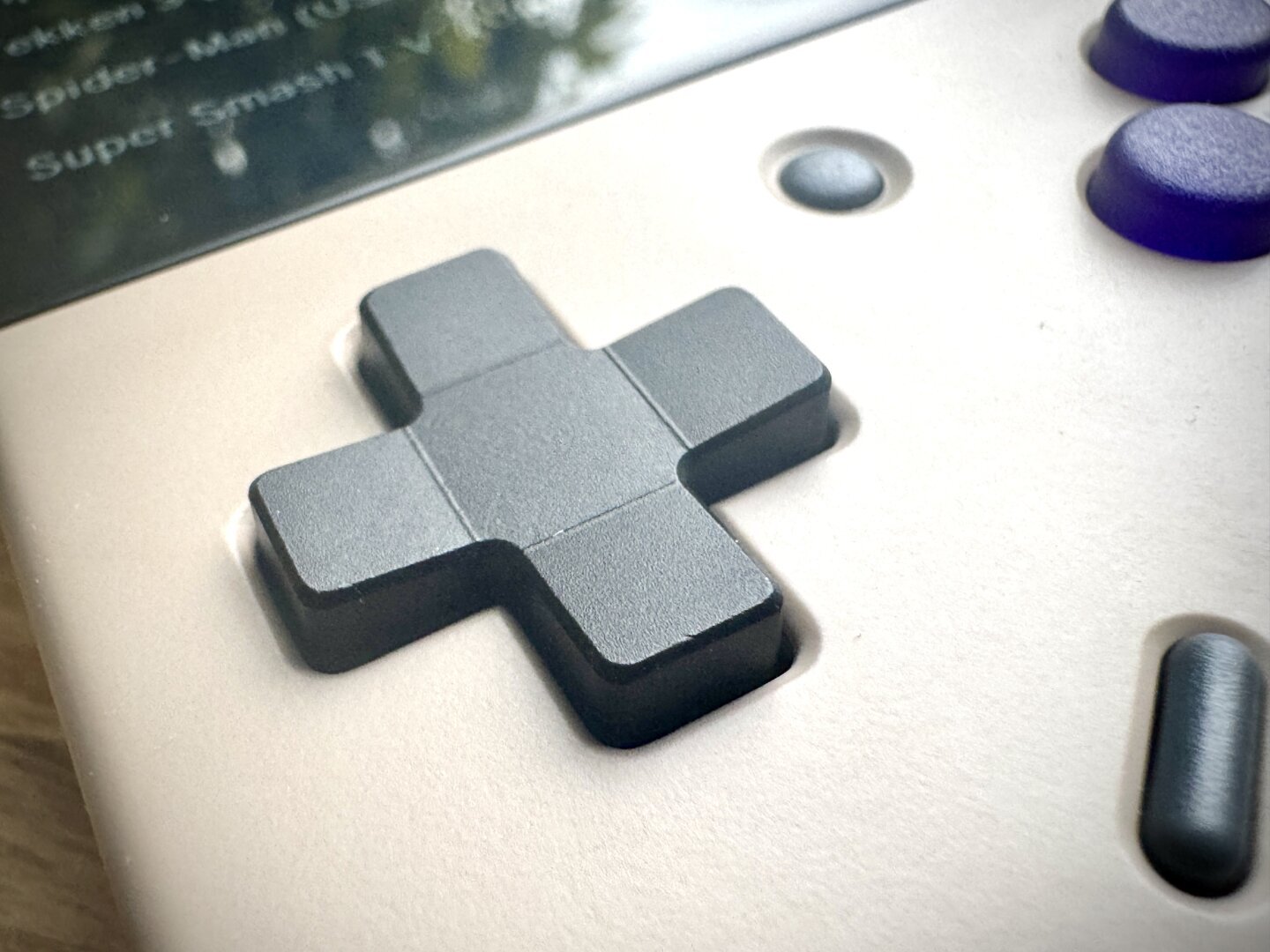 Close-up of a black D-pad on a retro gaming console, with slightly angled edges.