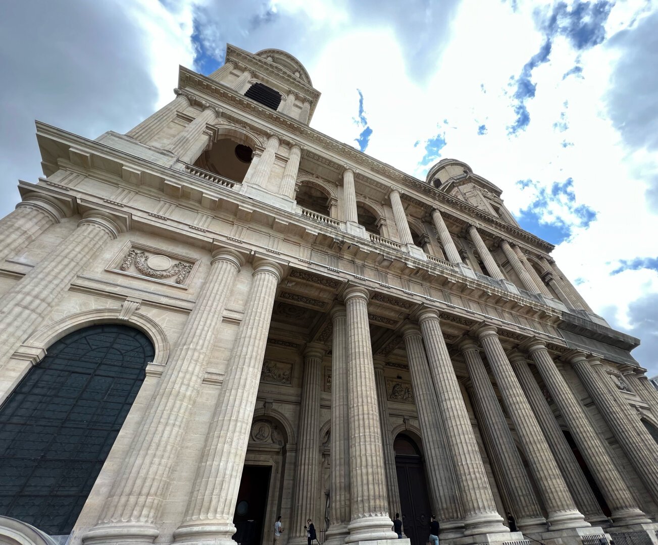 Façade de l'église en contre-plongée, avec sa galerie de colonnes et ses deux tours