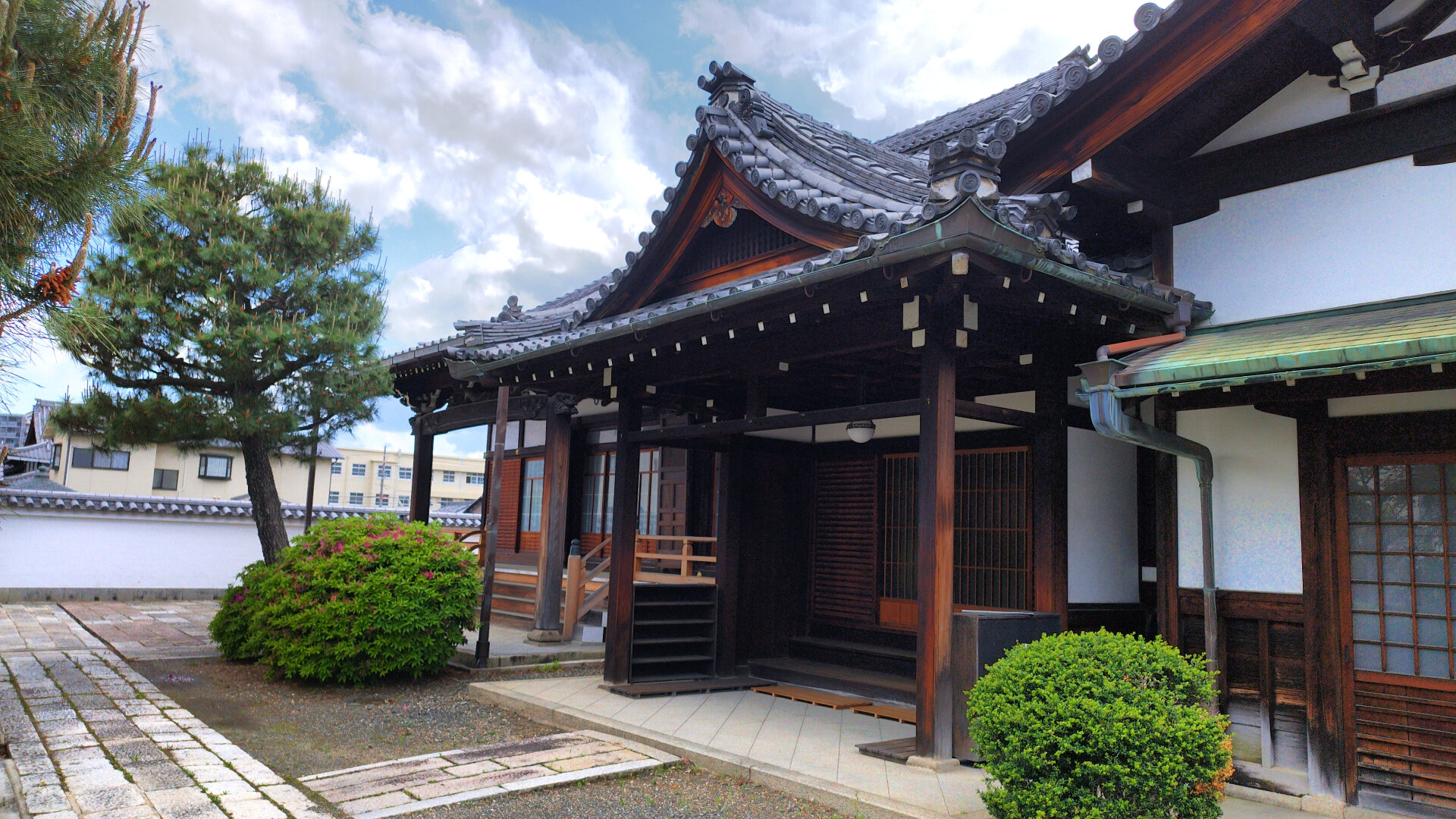 Entrance to a hall on temple grounds. Picture taken at an angle capturing some of the shrubs and trees as well.