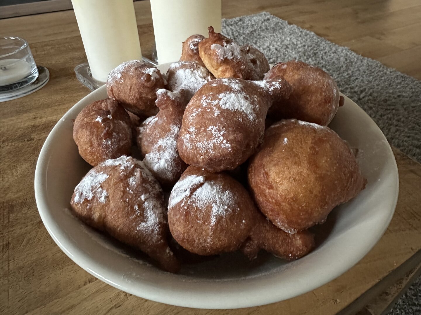 A bowl of freshly baked oliebollen with a sprinkling of powdered sugar.