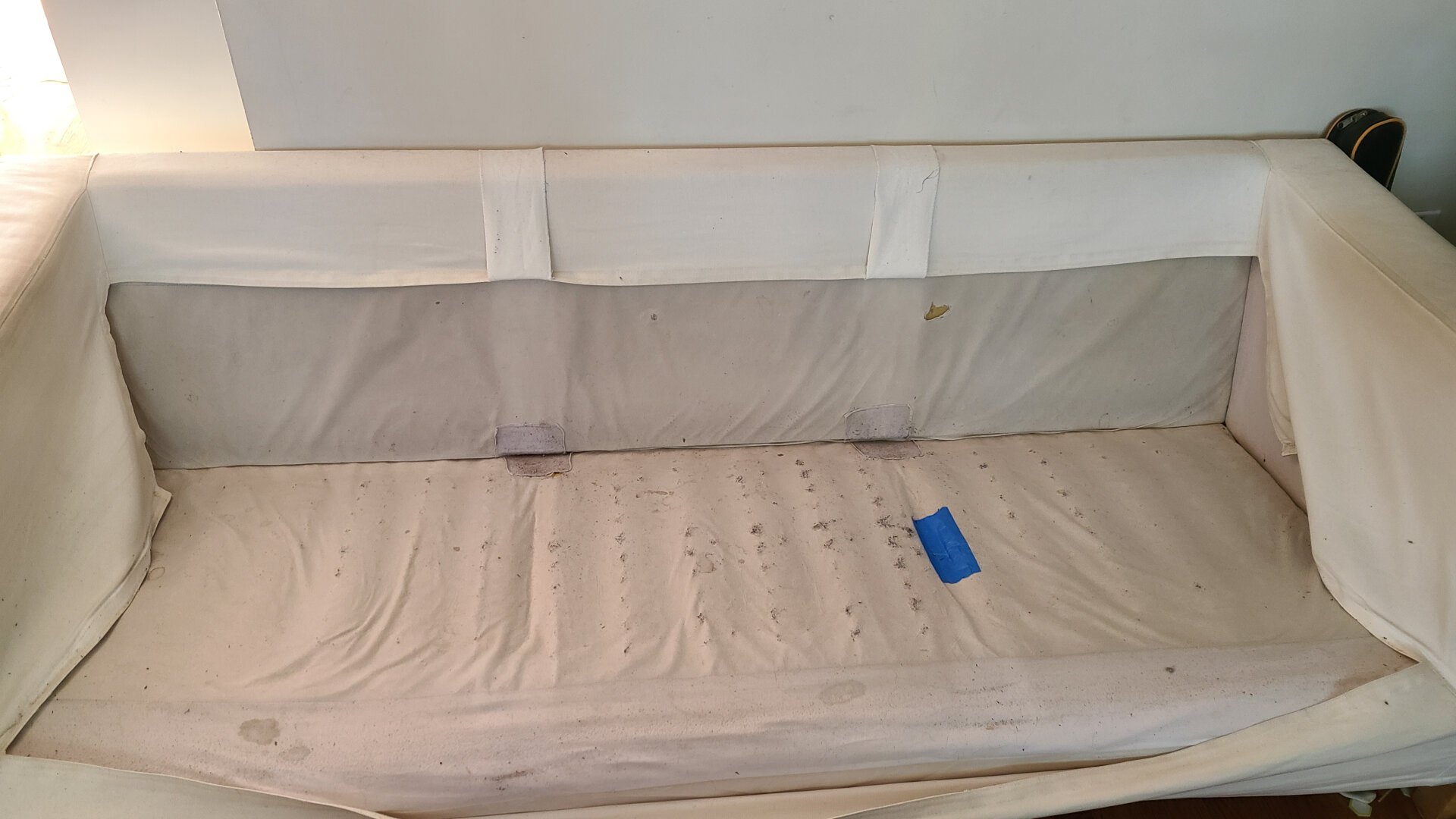An Ikea couch with the cushions removed. The fabric is wearing out and the springs are coming through. It's held together with tape.