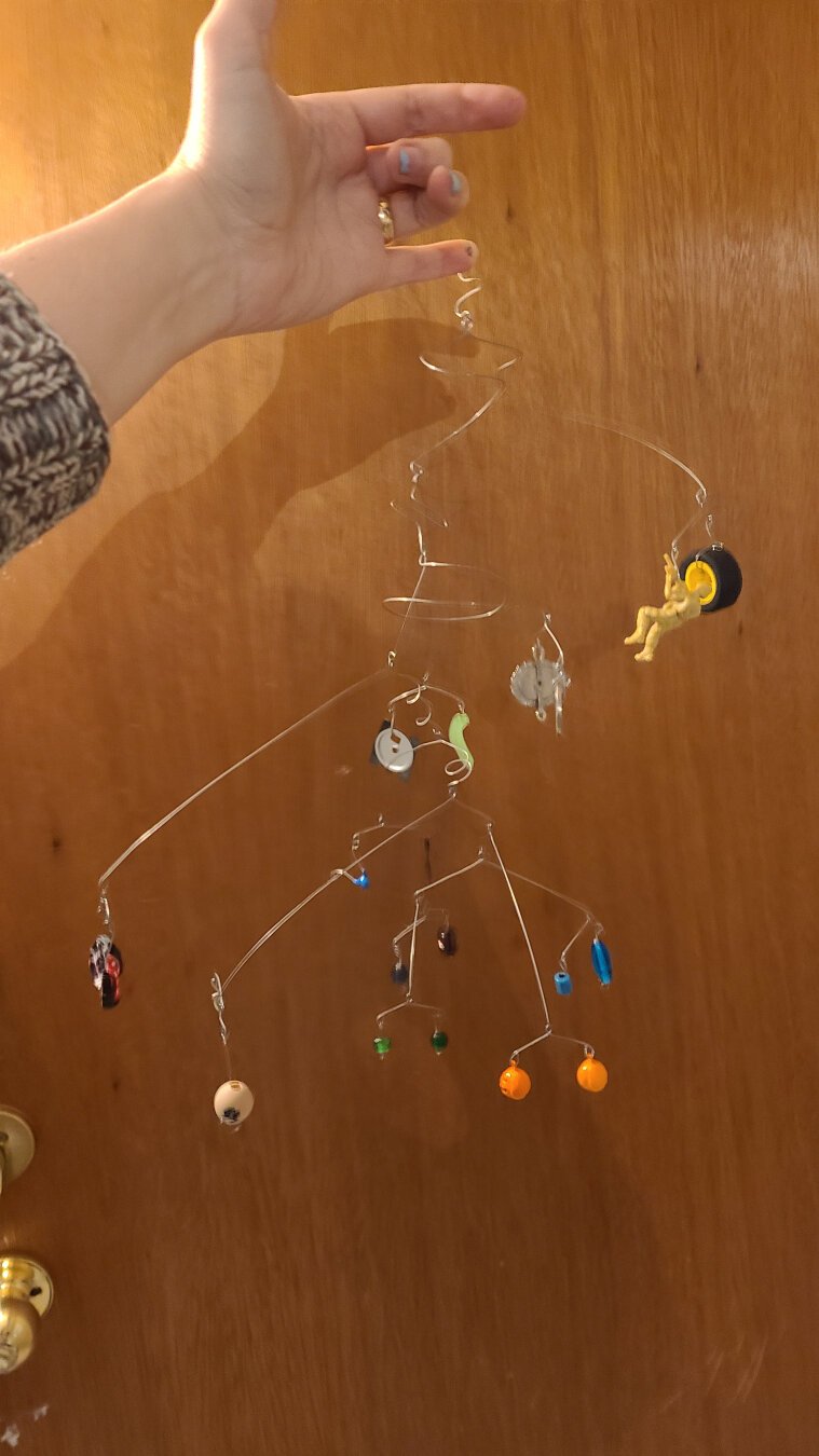 A wire mobile with a variety of objects suspended from it.