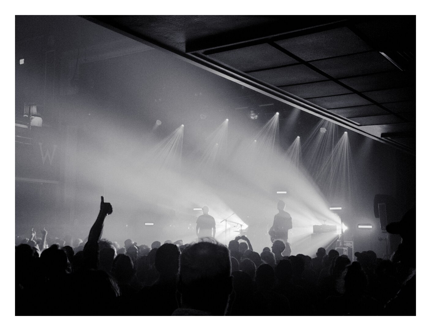 black and white photo of the silhouette of Botch playing on stage with a dude doing a big thumbs up in the crowd