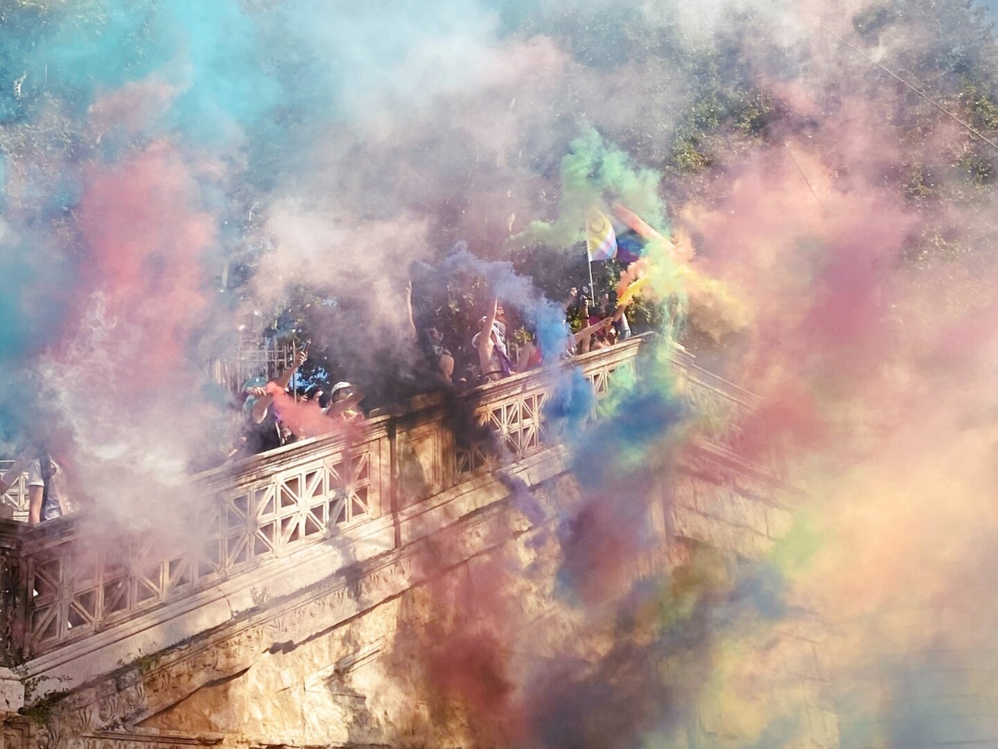 Gruppo di persone su una scalinata con fumogeni arcobaleno