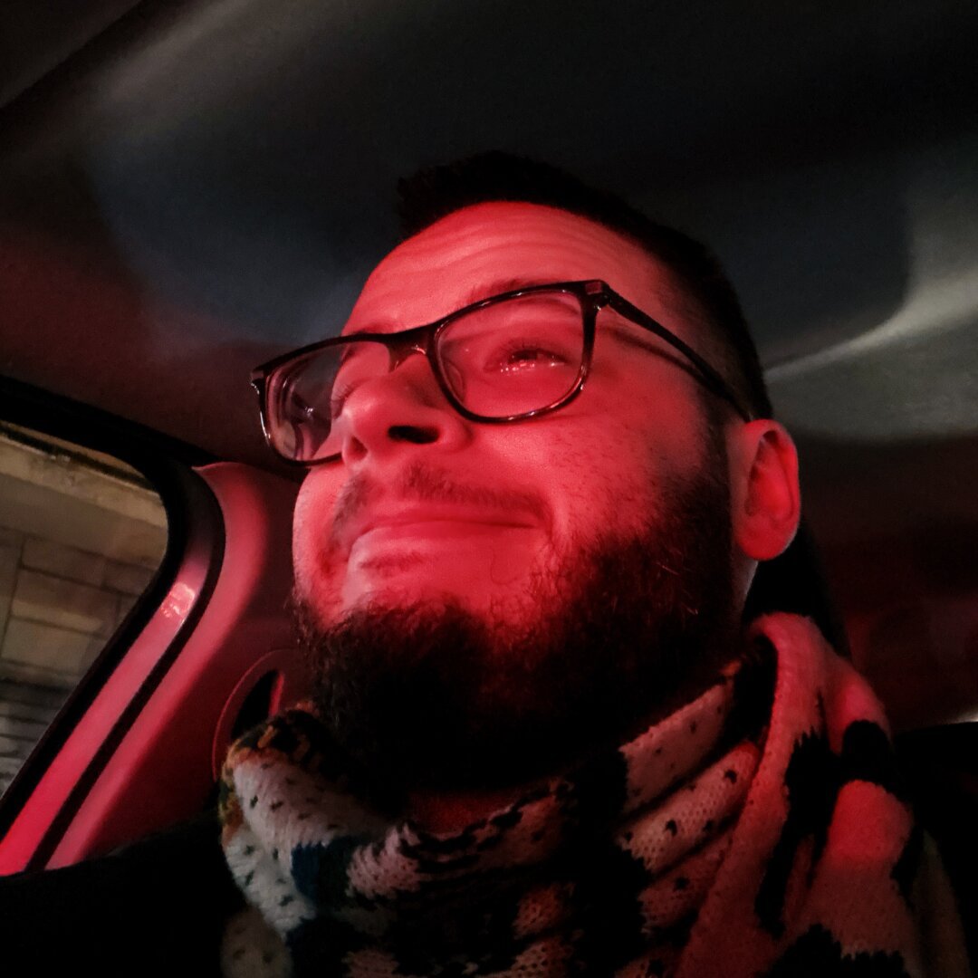 Me in the car lit up by a red light with a fake happy face