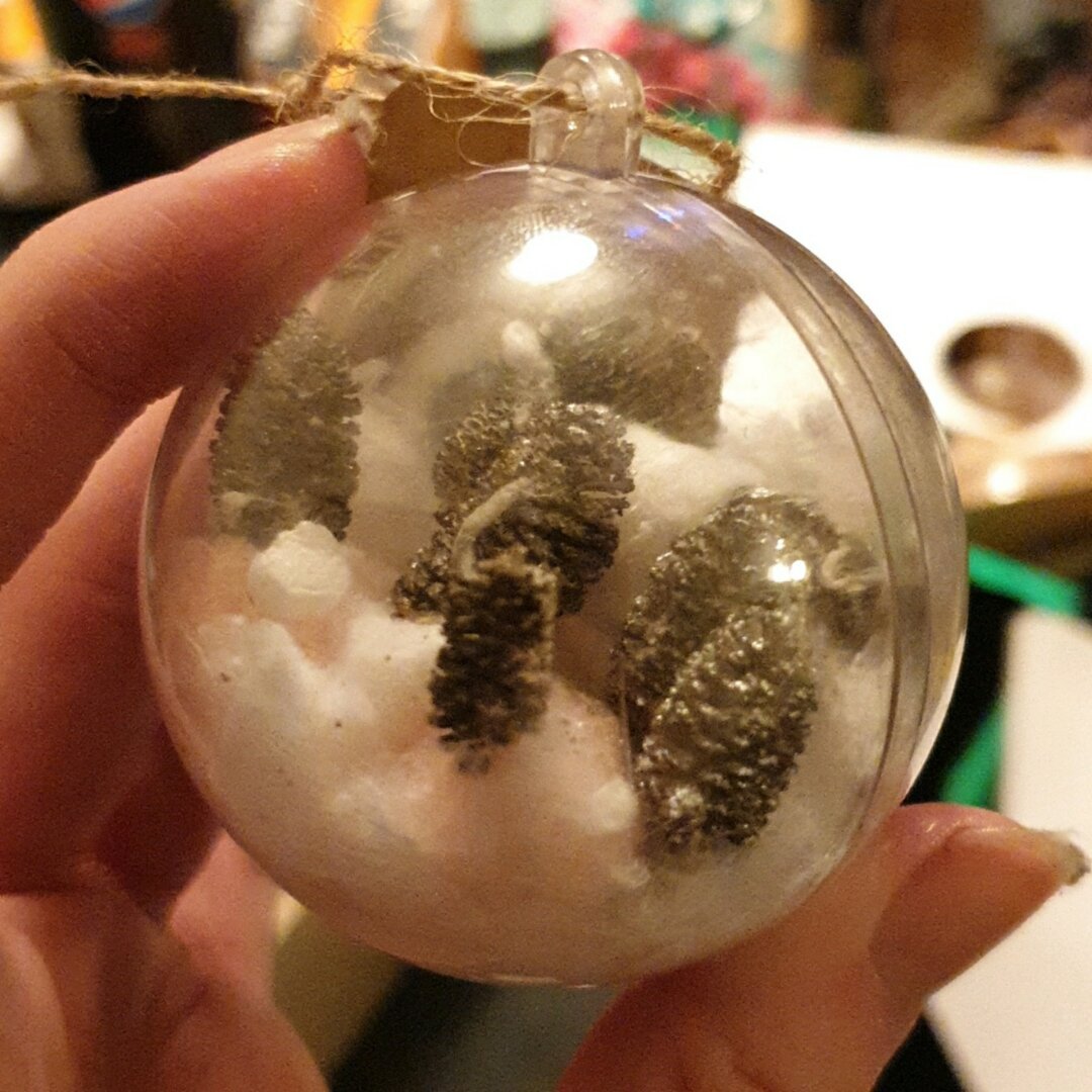 An Christmas bobble of snowy forest made with white cotton and mini pine cone