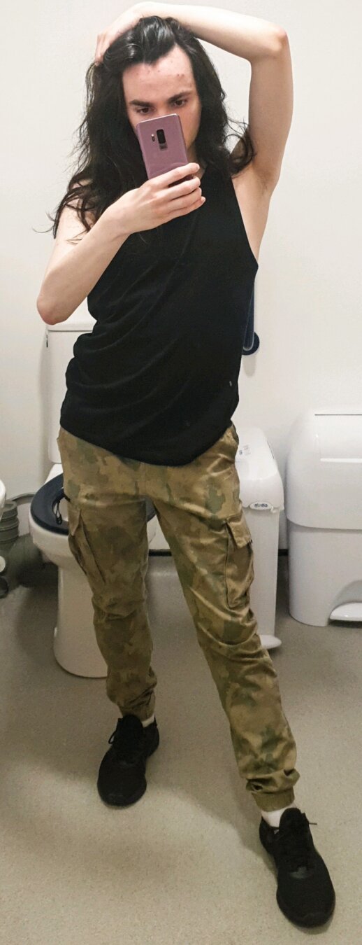 Mirror selfie of me wearing a black vest and cargo trouser and black trainer