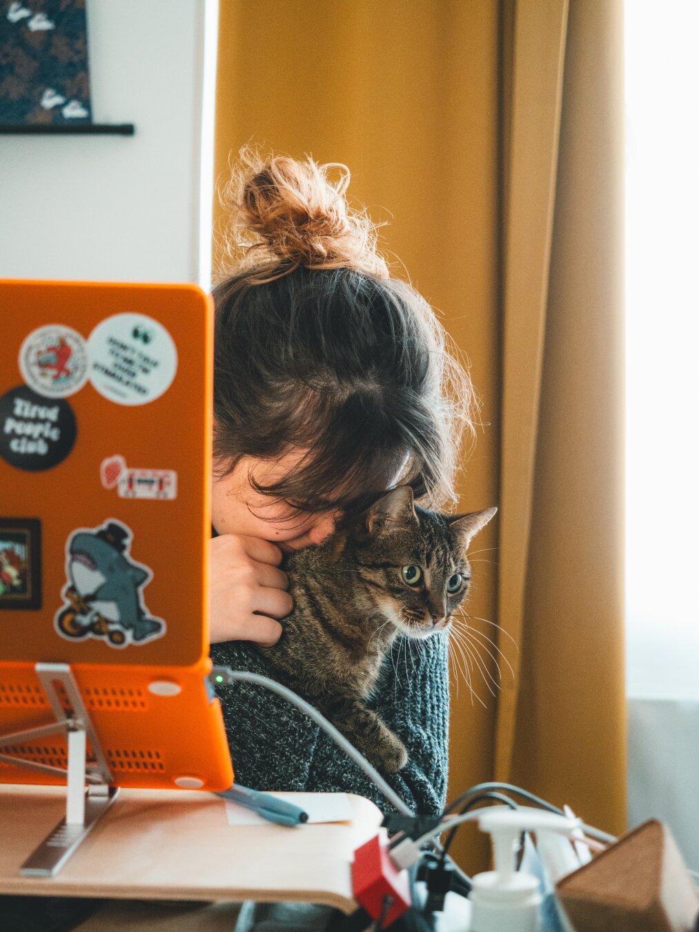 Photograph of a woman embracing a tabby cat