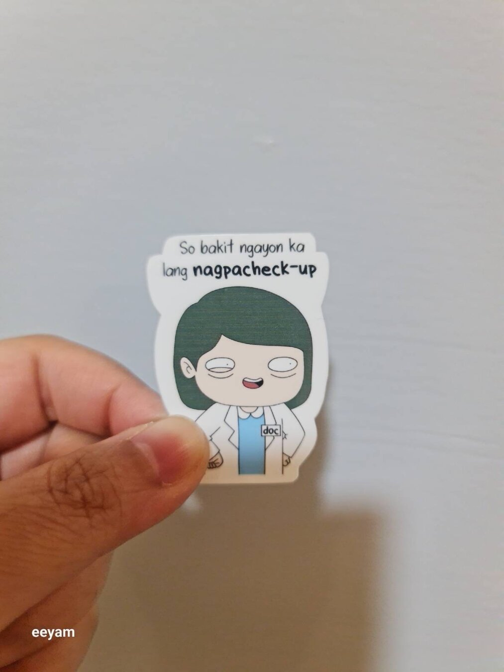 Sticker. Drawing of a female doctor, short black hair, white coat, eye bags, hands on her hips. Thought bubble: So bakit ngayon ka lang nagpa-checkup