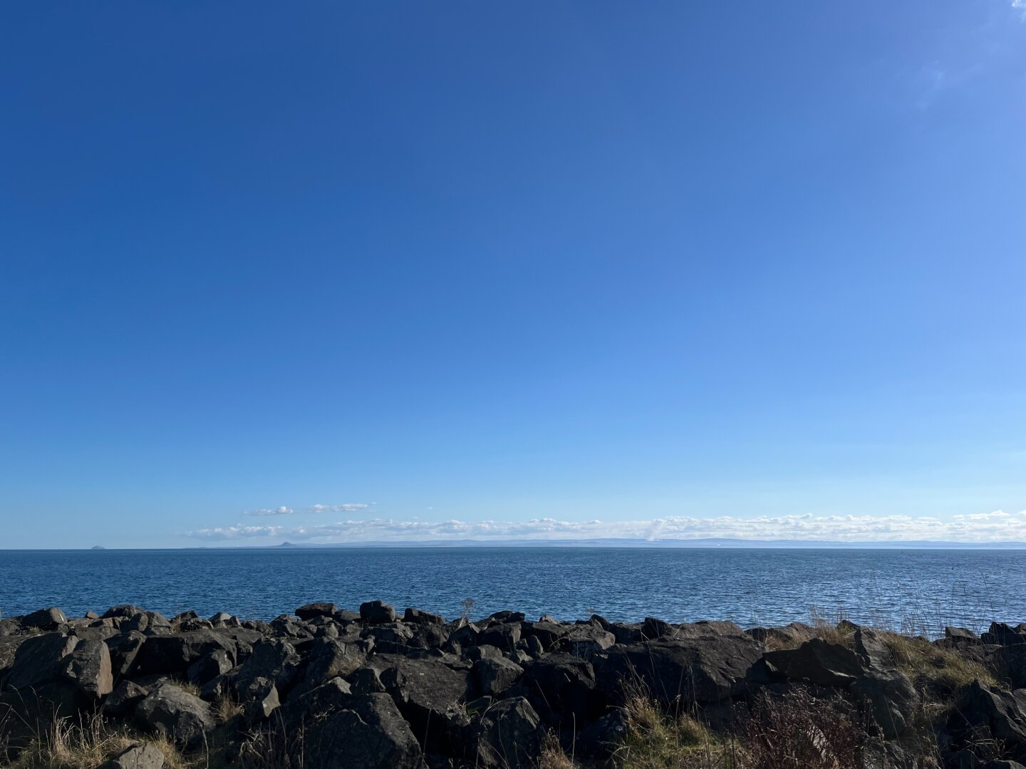 View onto the sea over some stones in the foreground.