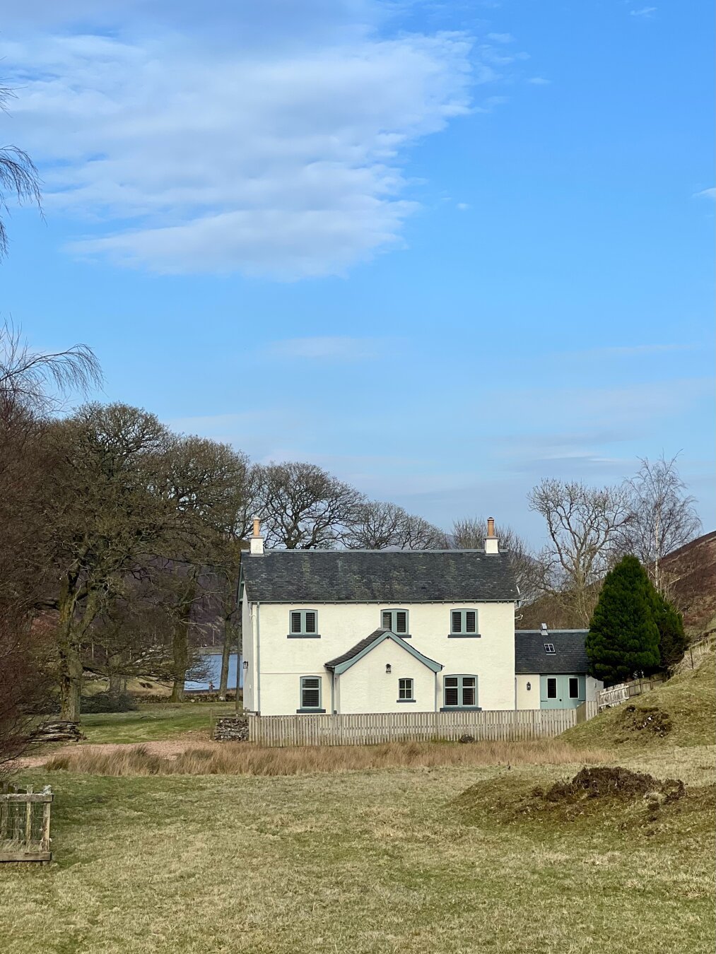 A white house in between some trees.