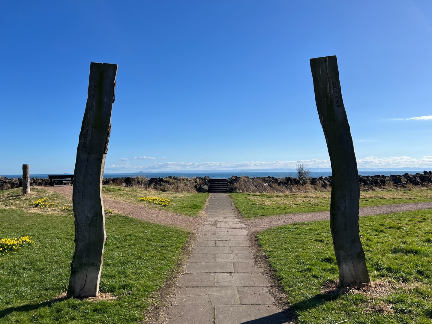 Path straight onwards framed by two wooden beams and the sea in the background.