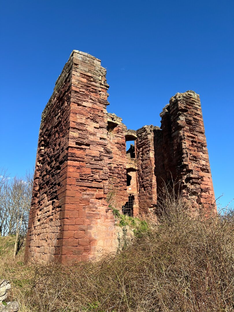 Red sandstone castle tower ruins.