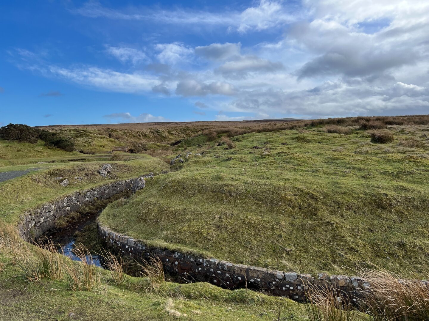 Greenock cut‘s beautiful masonry at a bend in the lovely green grass landscape. A lonely bench in the background.