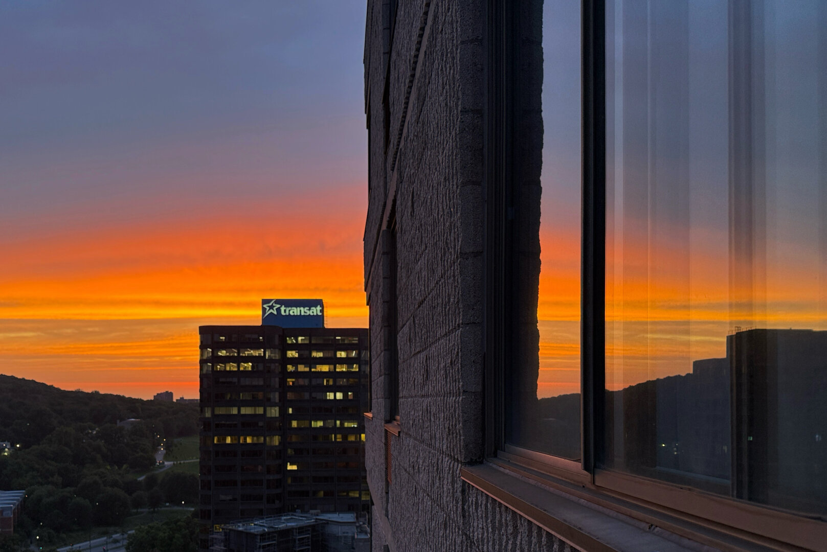 Brilliant orange in sky reflected in window, office tower in background