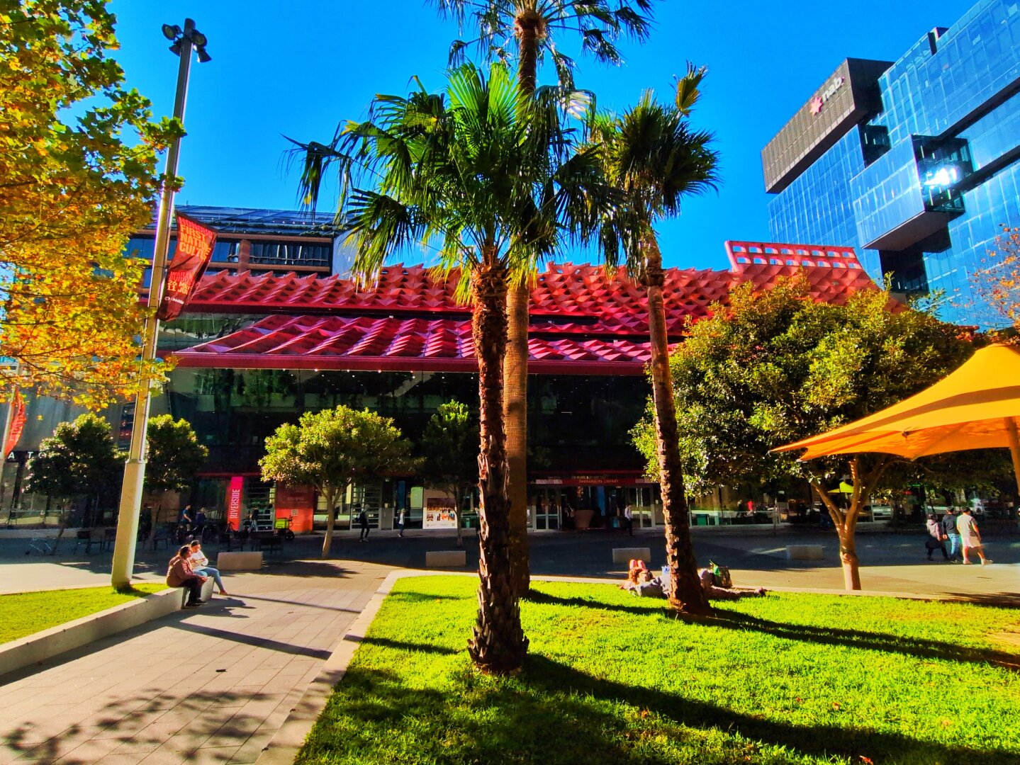 In front, there are trees, grass, and umbrellas.
