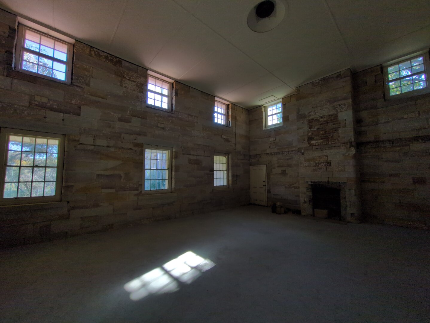 Another large two-storey-tall room, this time with sandstone walls and a fireplace. Despite two rows of windows, and the fact it's broad daylight with a blue sky outside, it's very dark.