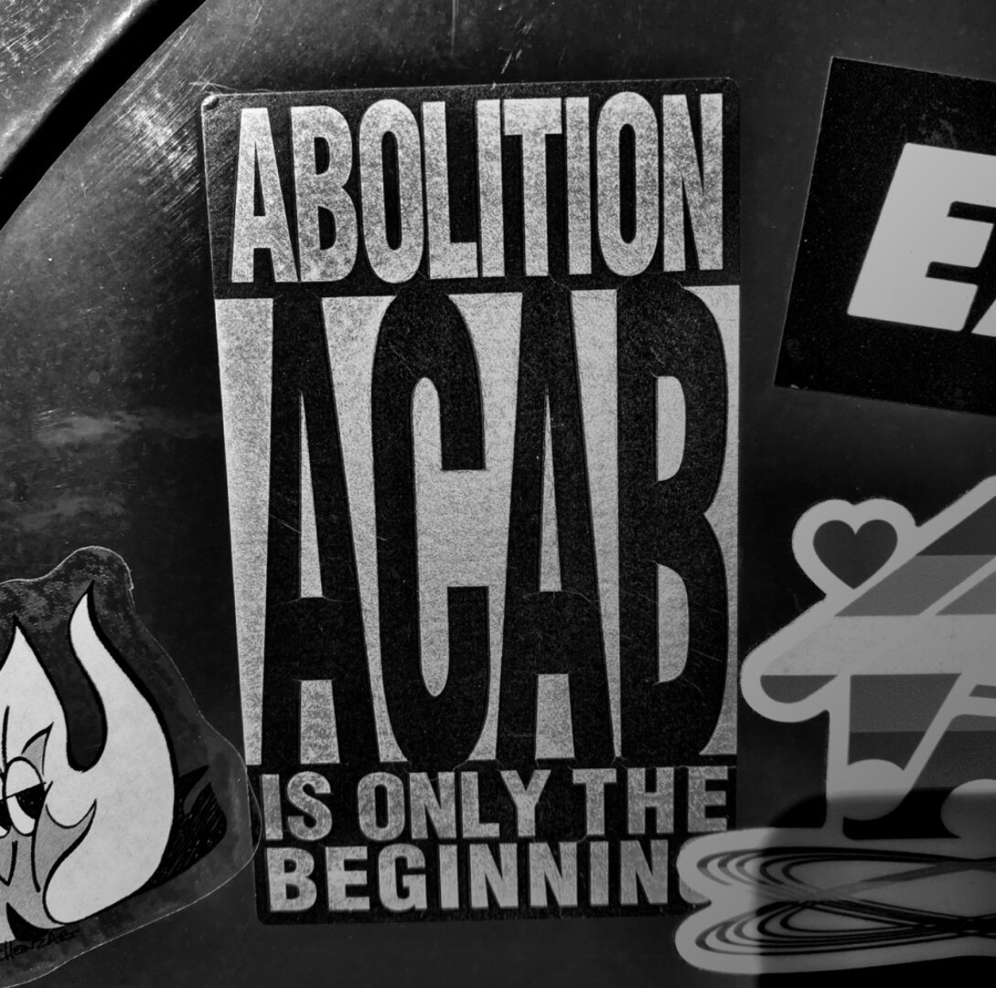 Duotone sticker posted over metal mailbox that reads: “ACAB - Abolition is only the beginning”