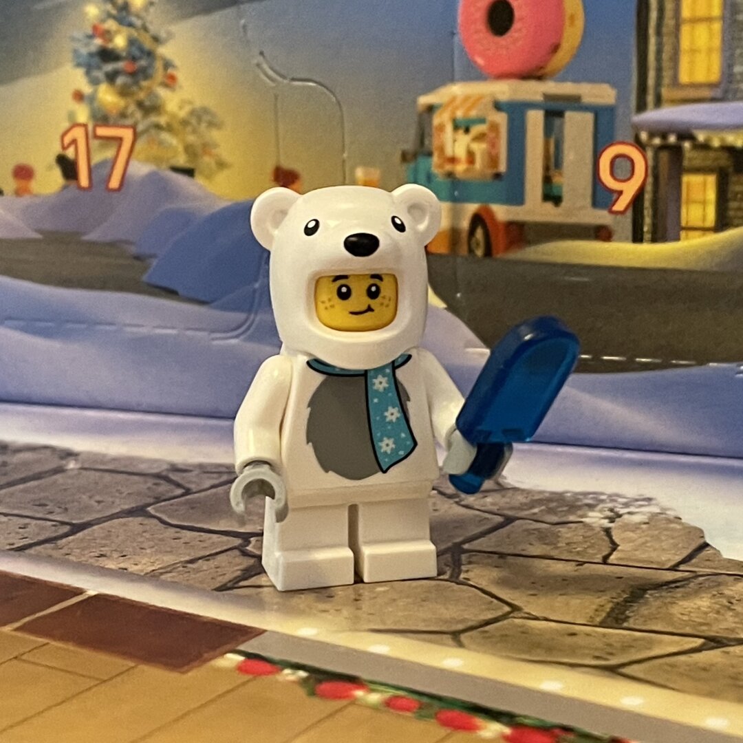 LEGO mini figure wearing a polar bear costume and holding a translucent blue popsicle.