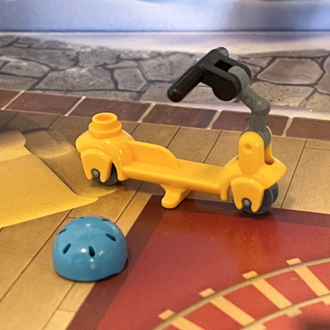 LEGO minifigure yellow scooter with a blue helmet sitting to the side.