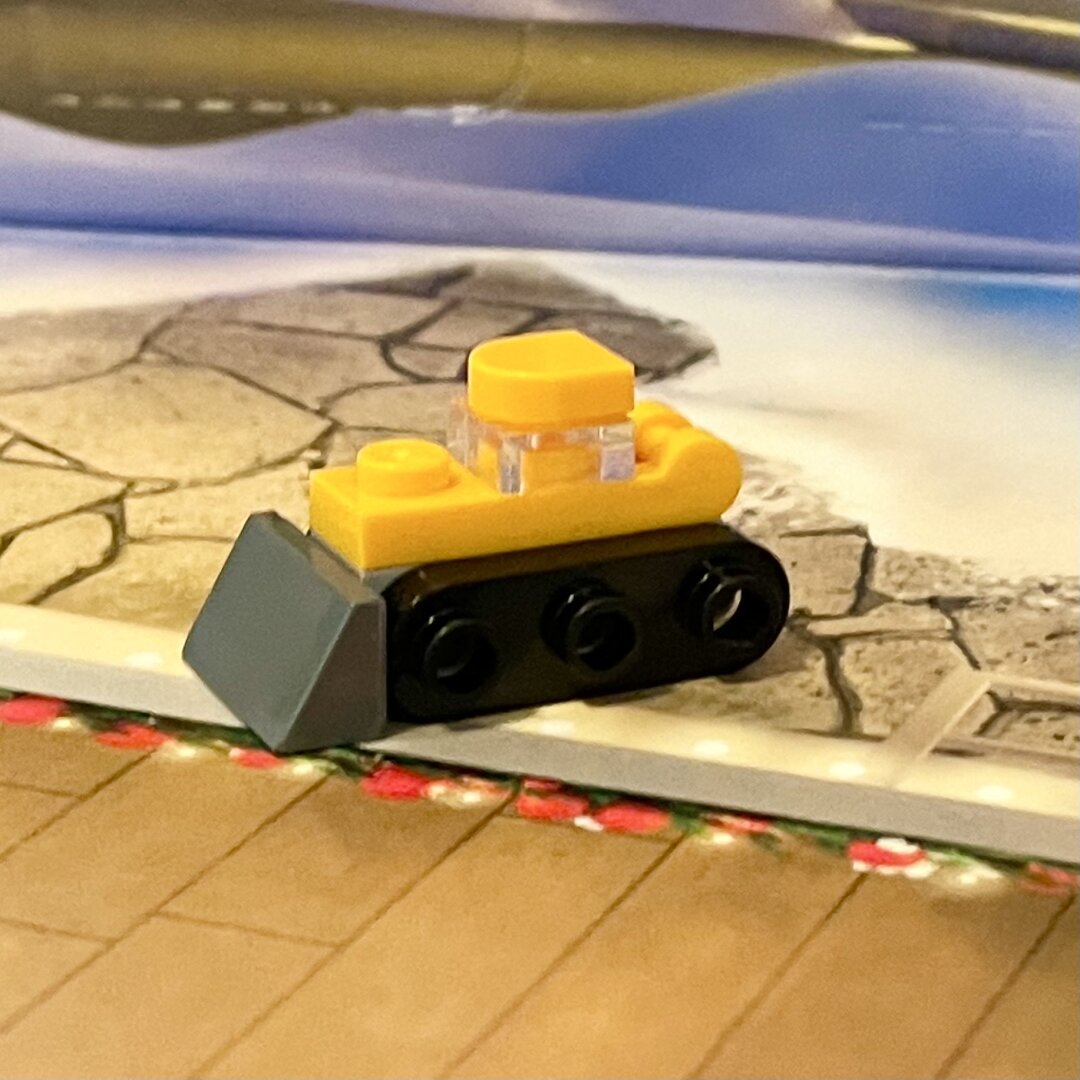 LEGO bulldozer mini build. It’s yellow with a grey scoop and black treads.