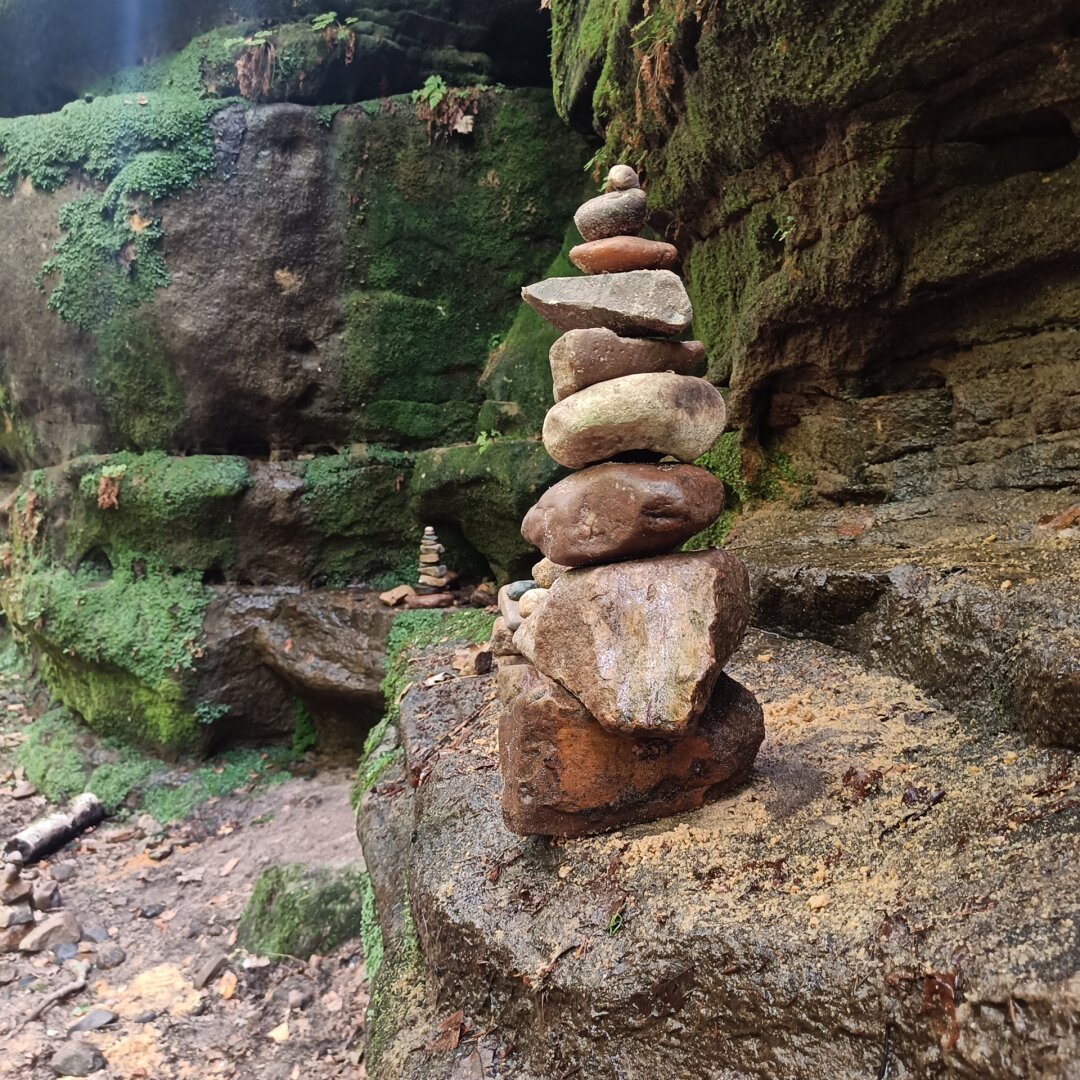 A small tower of stacked stones in front of a mossy boulder