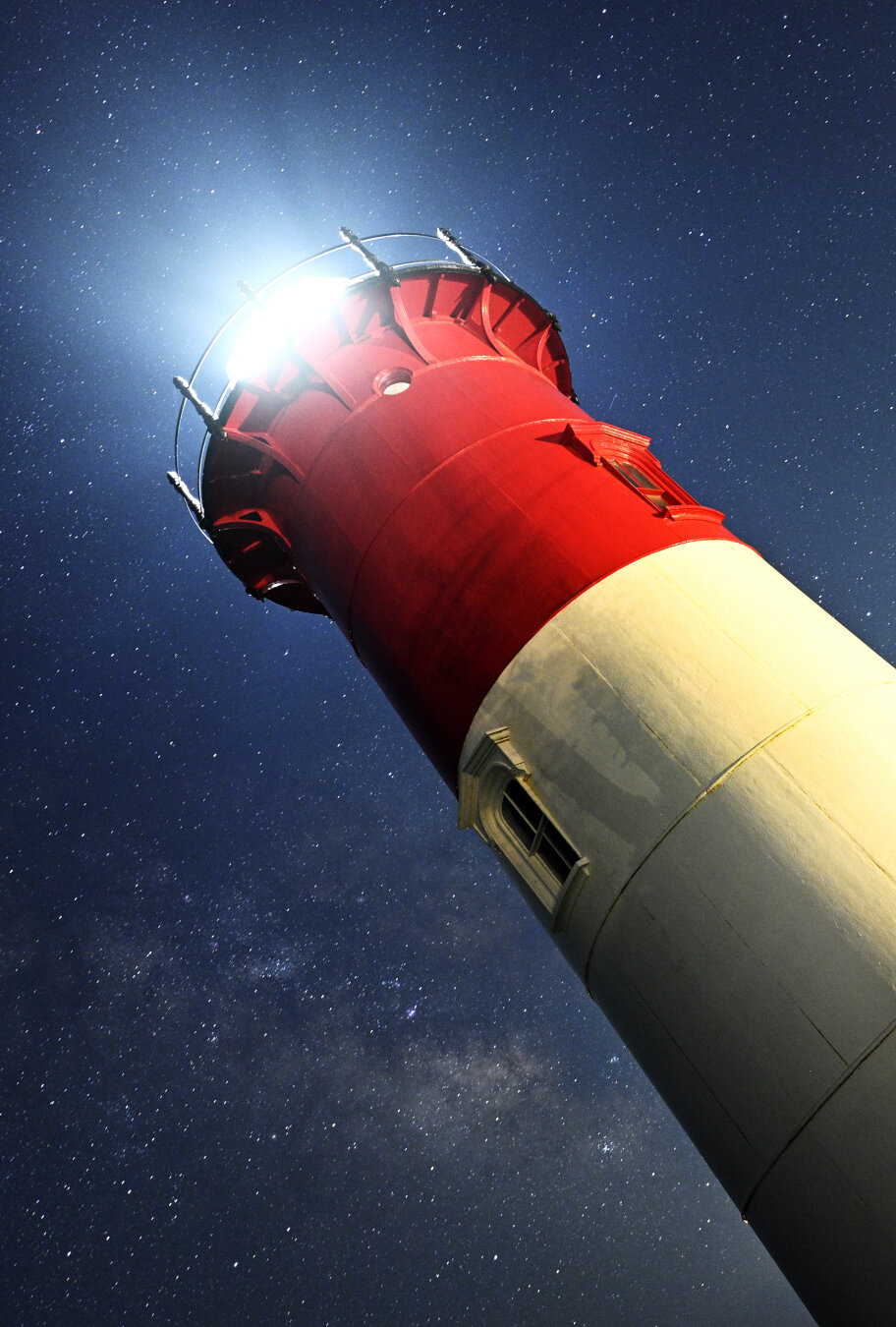 A Dutch angle shot of Nauset Light, famous from the packaging of Cape Cod brand potato chips, against the night sky.