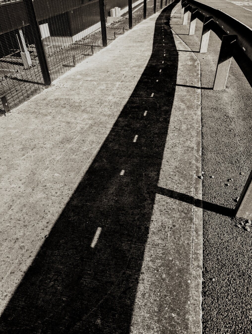 Shadow from crash barrier creates the impression of another road.