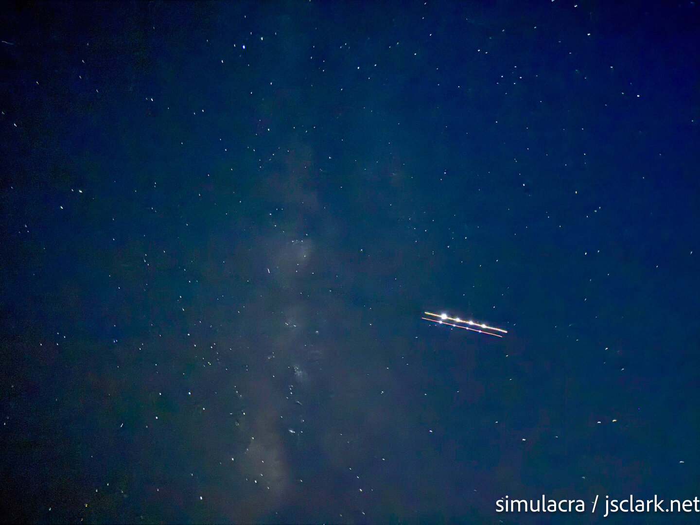 3-second exposure of night sky with Milky Way and light streak from an aircraft.