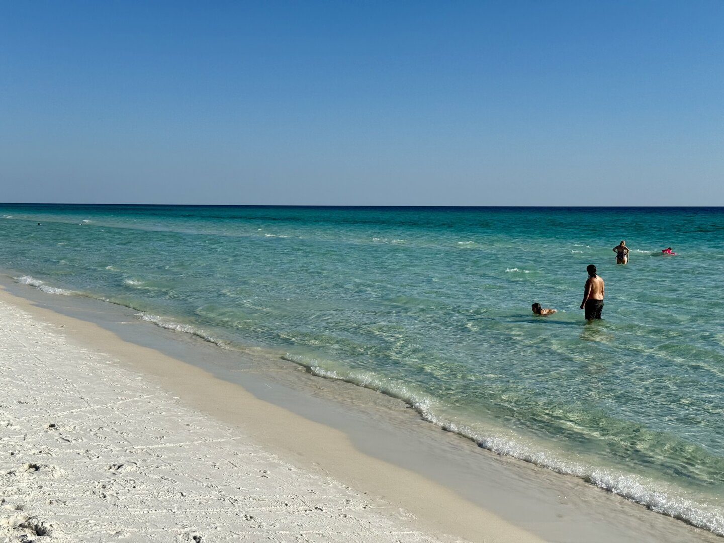 Turquoise clear water, white sand, a few bathers.