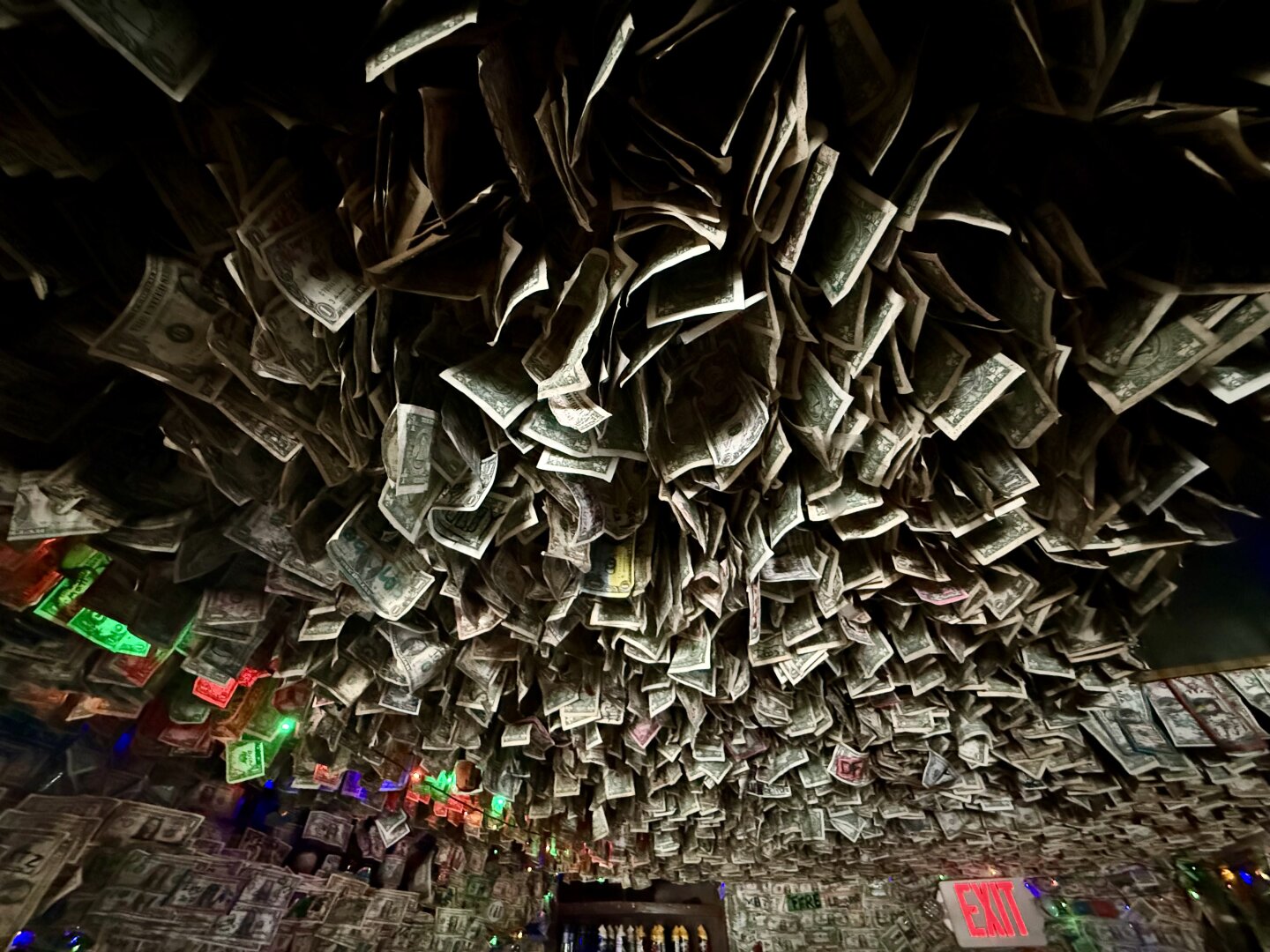 Mass of dollar bills hanging from pub ceiling.