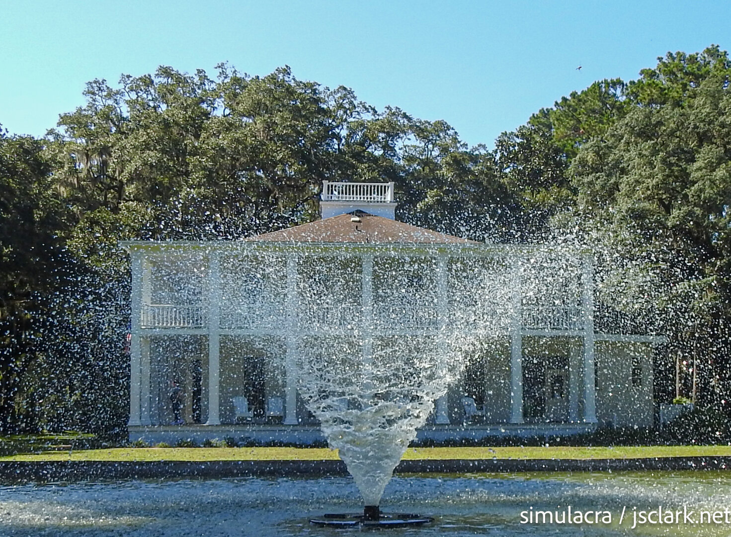 Water spray fountain with a large manor house in the background.