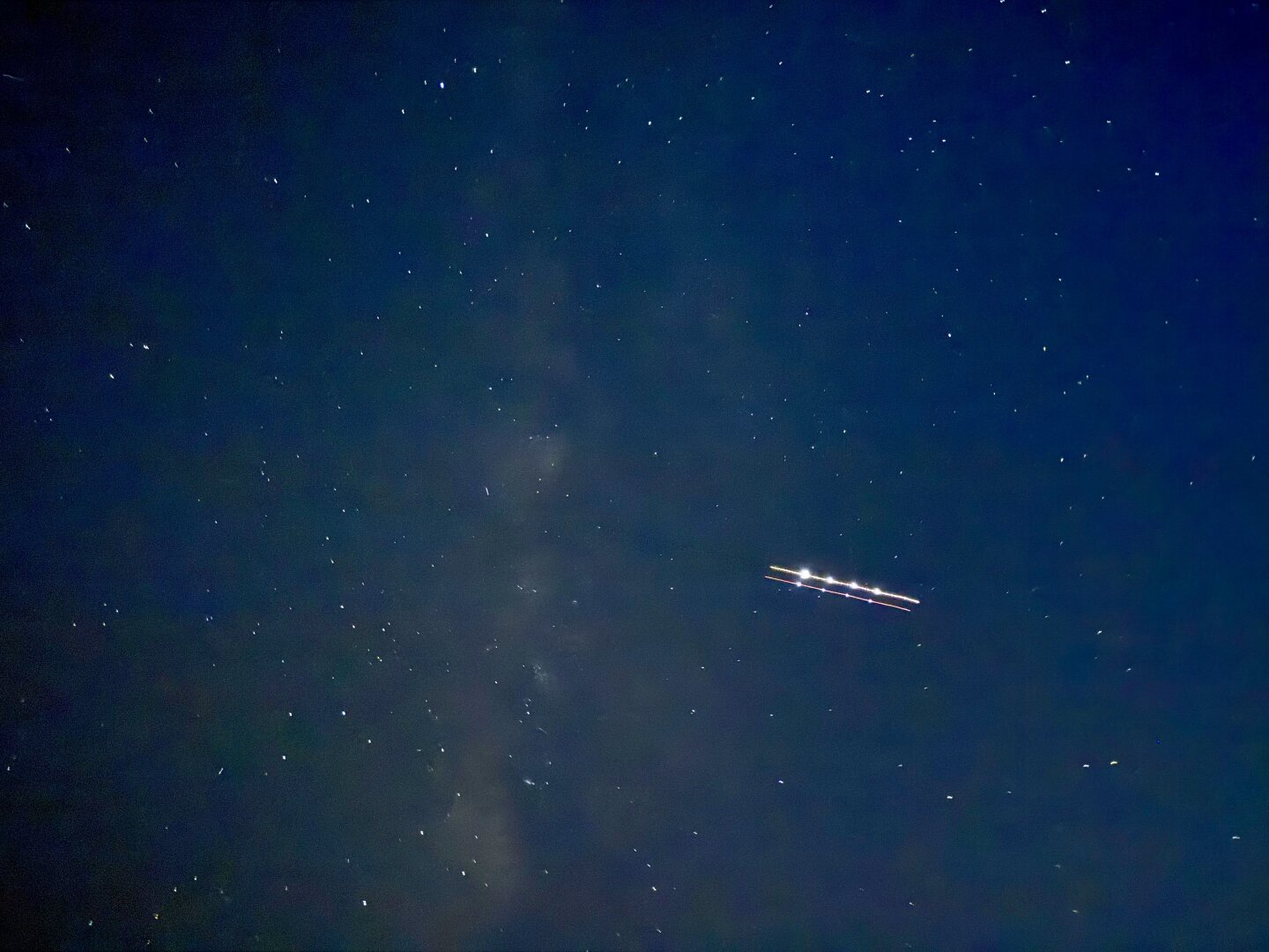 Night sky with portion of Milky Way.  Time-exposed airplane trail.