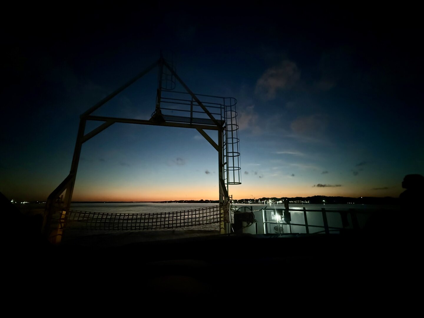 Deepening blue over sunset sky, river and bow structure of ferry.