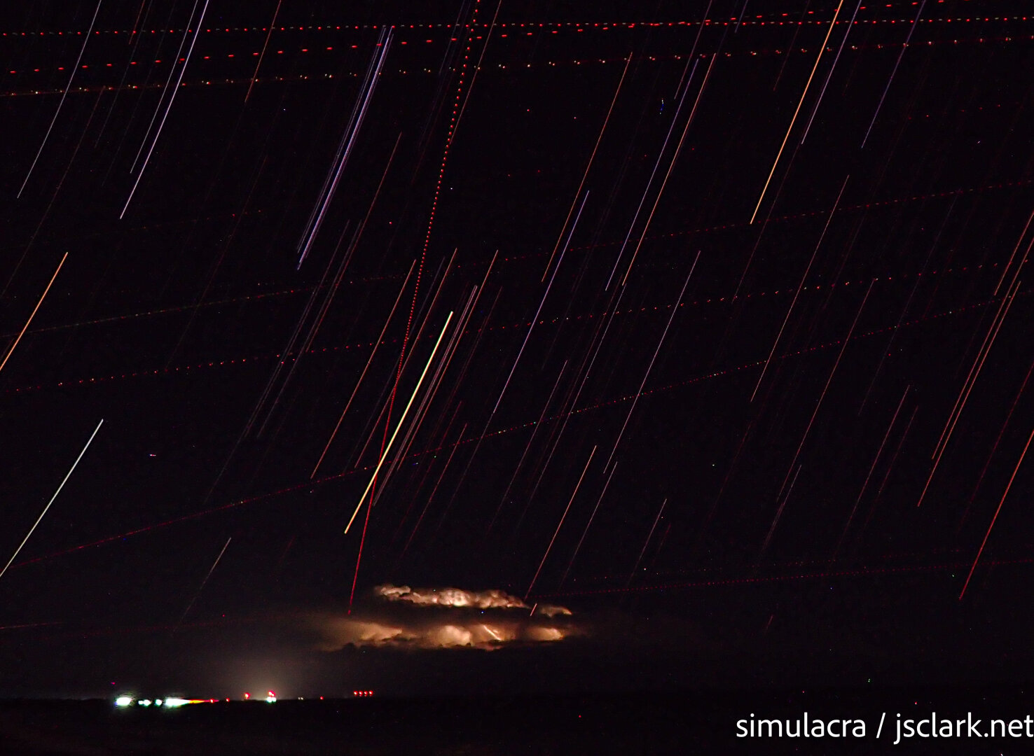 Time-exposure night shot with star trails and distant lightning.