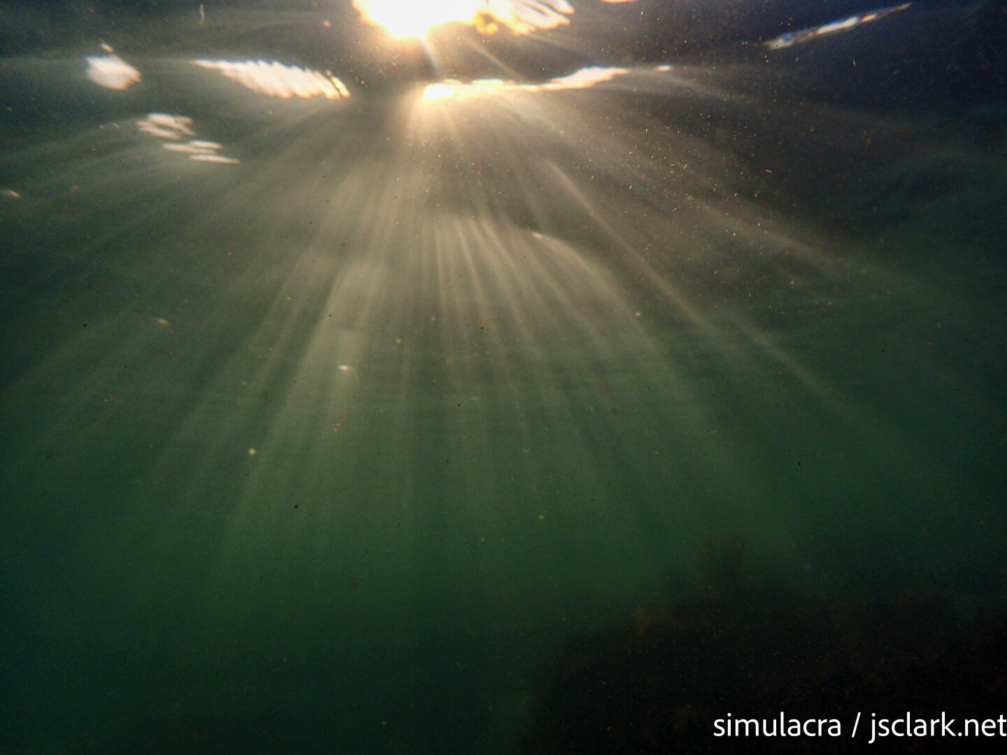 Beams of sunlight scattering through clear salt water.