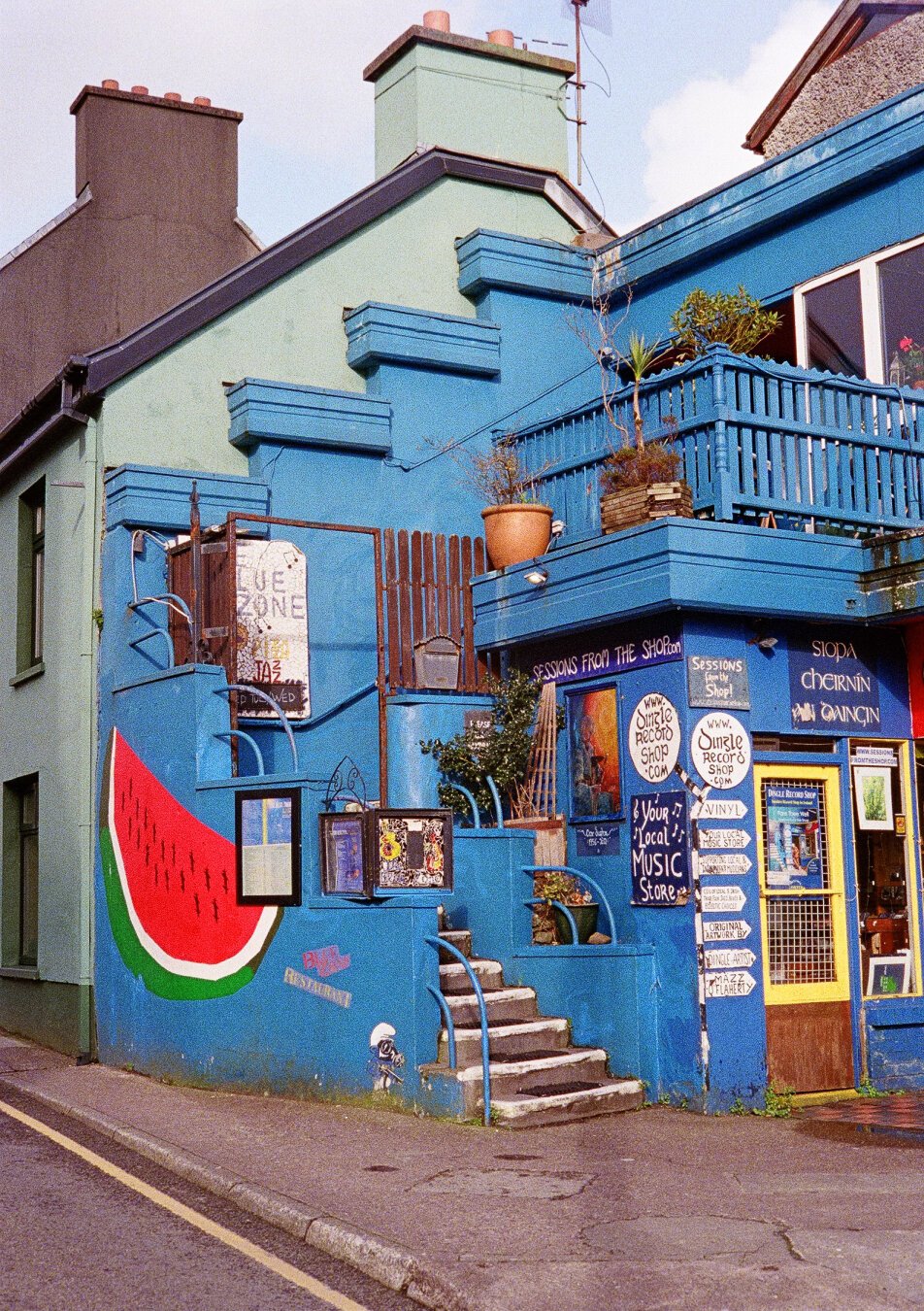 The Dingle Music Shop, a small building painted in blue with many colorful accents.
