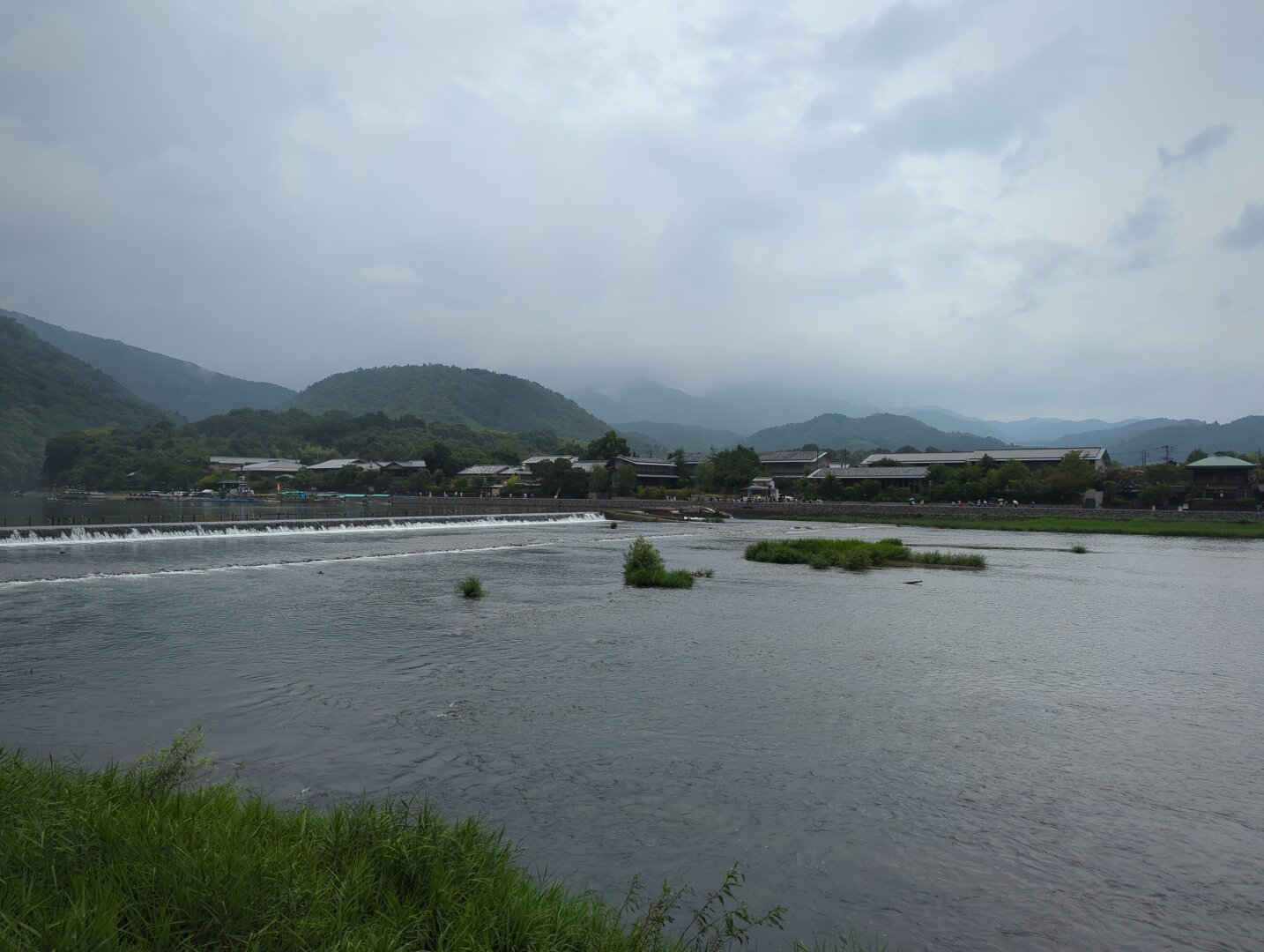 Arashiyama Kyoto landscape. Background of rolling green hills (uncooperative gray weather). Foreground of a large waterway on the northern side of Togetsukyo bridge (off screen).