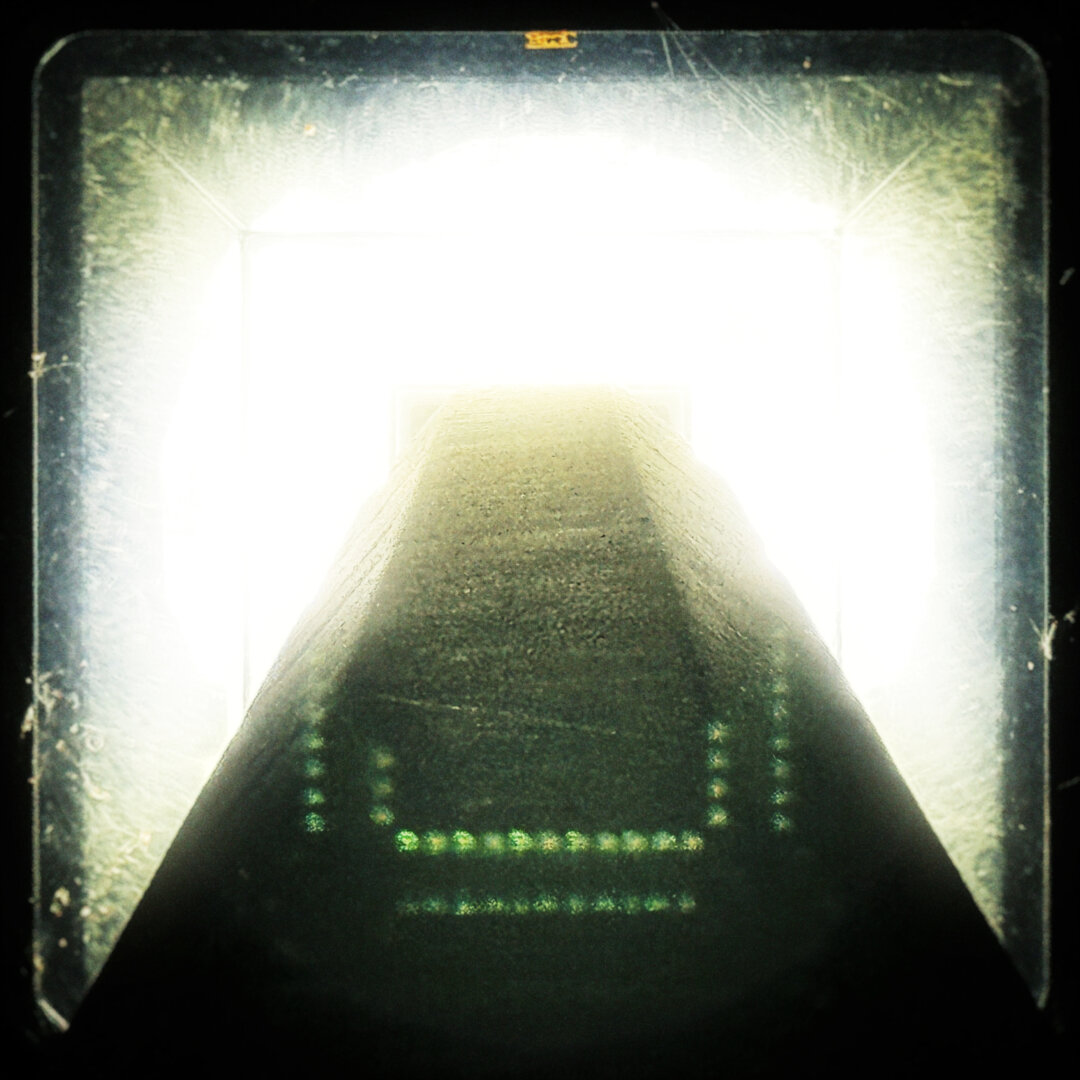 A view from straight up an outdoor lamppost reveals a bright light filling most of the frame.