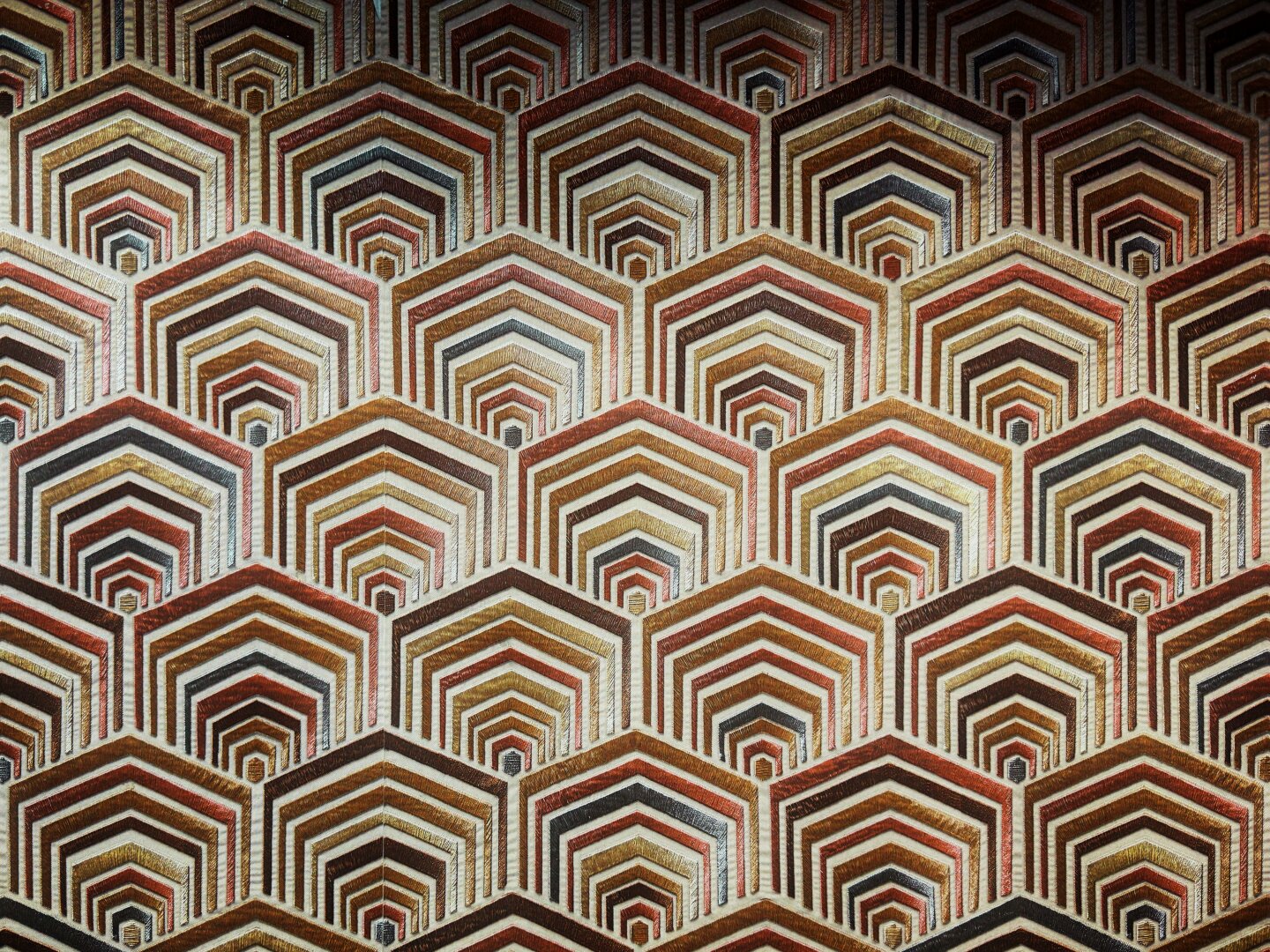 Muted blue, red, and orange hexagon patterns layer over each other, filling the frame with their lightly raised concentric lines.