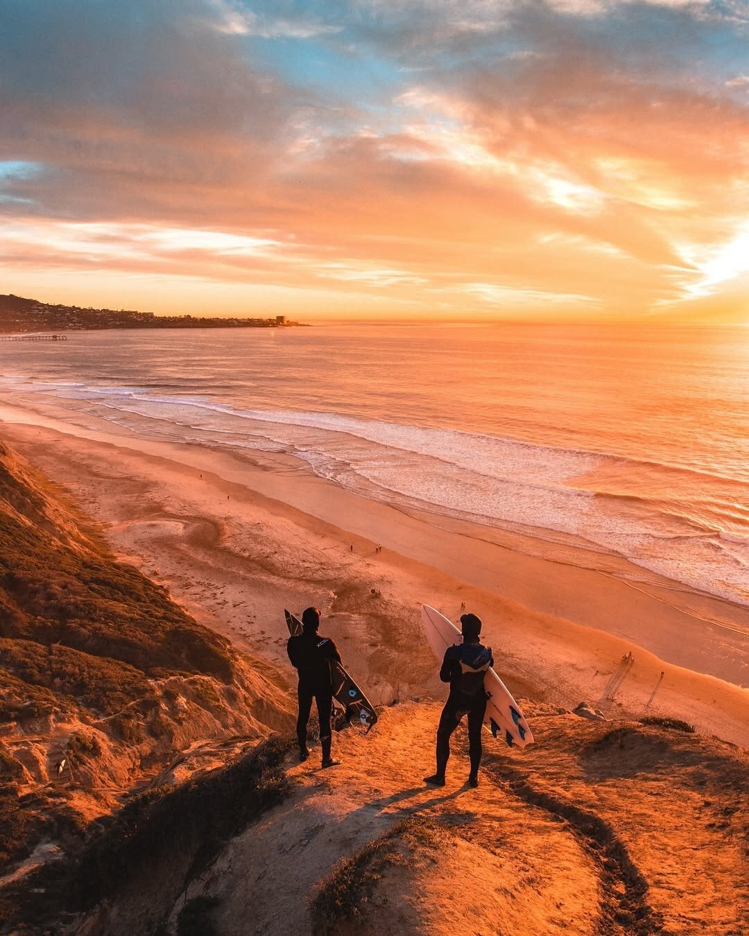 Two surfers watching the sunset in San Diego.