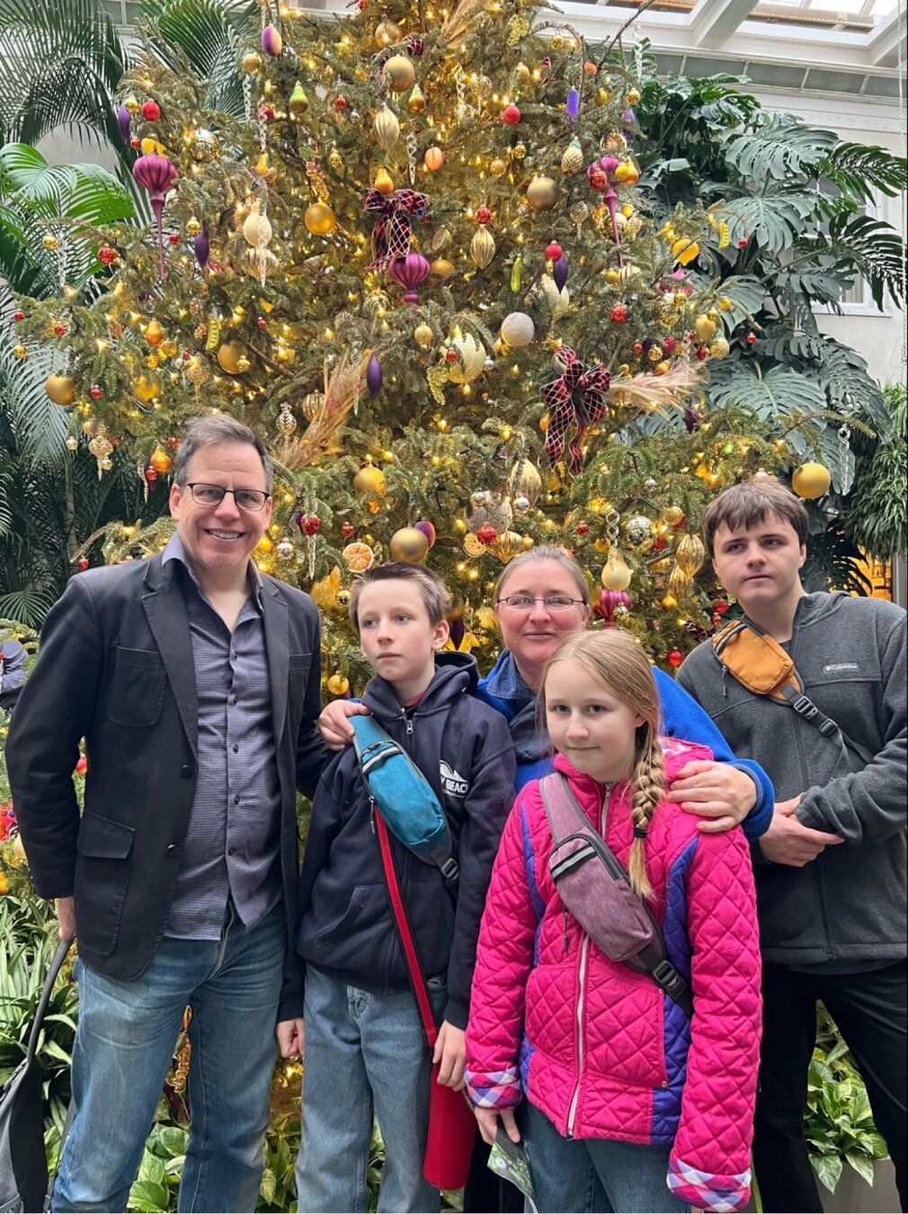 Five family membera in front of Christmas tree.