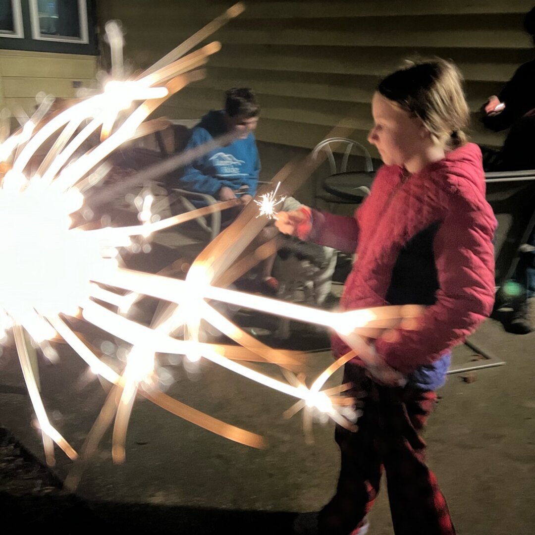 Laura passing behind sparkler in foreground.