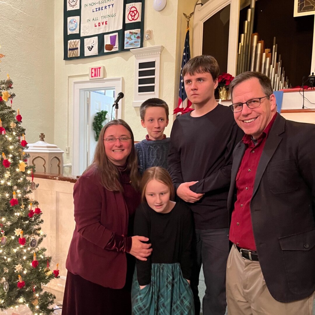 Family photo in a church  in which only the parents are smiling for the camera.