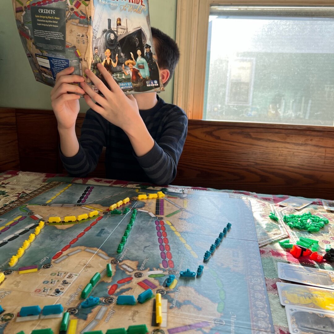 Picture of a player of Ticket to Ride checking instructions.