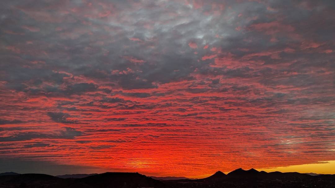 red glow from the sun reflecting on rippling clouds in the sky after sunset