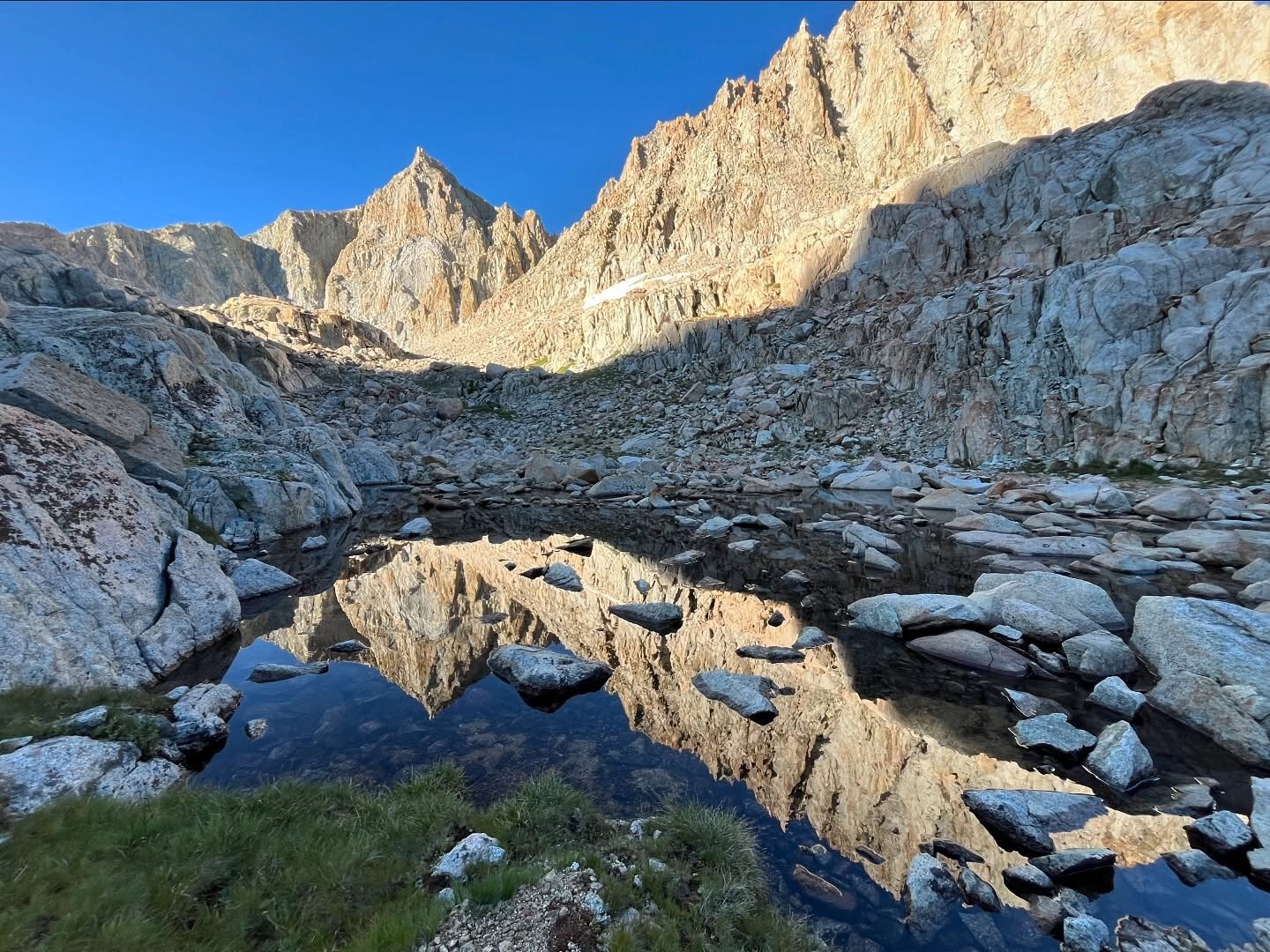 high alpine cliffs rising to peaks and reflecting in a lake