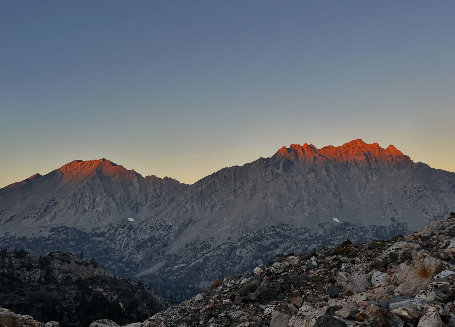 Tips of mountains catching the last red light of sunset as it gets dark all around